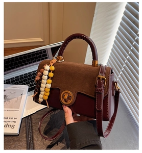 Detail of retro color-block handbag with gold twist lock and woven handle