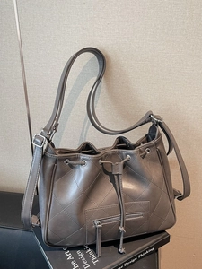 Deep grey quilted bucket bag with drawstring closure and adjustable shoulder strap