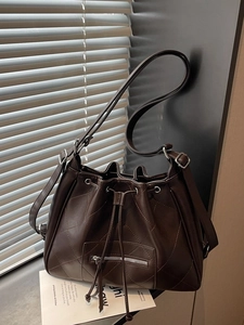 Minimalist dark brown quilted leather bucket bag with drawstring and adjustable strap