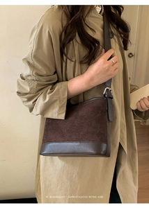 Detail of dark brown suede and leather shoulder bag worn with a green trench coat