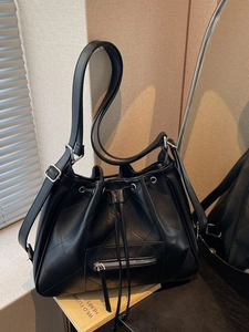 Minimalist black quilted bucket bag with drawstring and silver hardware on a shoulder strap