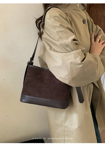 Detail of dark brown suede patchwork shoulder bag worn with a khaki trench coat