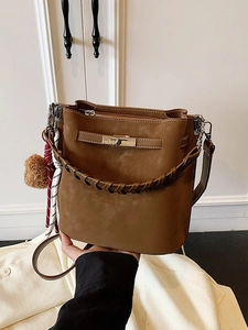 Vintage brown suede bucket bag featuring woven handle and metallic twist lock closure