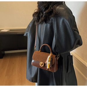 Detail of vintage brown leather handbag with round metal lock and colorful beads decoration