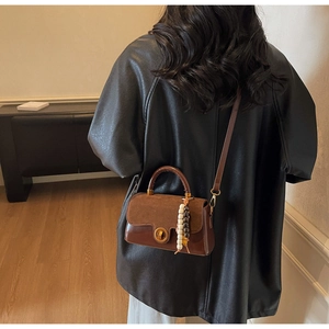 Detailed view of vintage brown leather handbag featuring matte suede panels and beaded charms