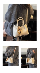 Detail of off-white crossbody bag with metal lock and decorative wooden bead charm