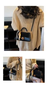 Detail of black crossbody bag with mixed leather, suede texture and beaded bag charm
