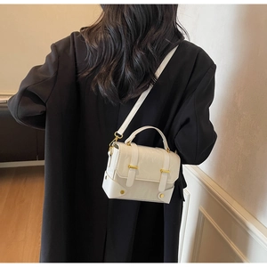 White minimalist mini square bag with gold hardware worn as a crossbody on model