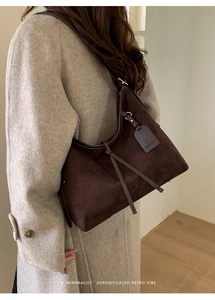 Détail du sac cabas en daim marron foncé avec lanières décoratives et fermoir magnétique