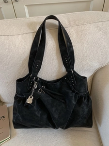 Vintage black suede tote bag with silver studs and star pendant on a soft sofa
