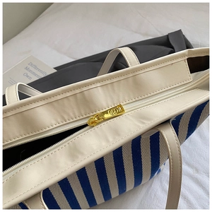 Macro view of golden metal zipper and striped fabric on a casual shoulder bag