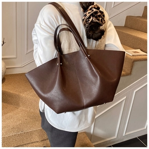 Detailed view of the dark brown wing-shaped leather tote bag worn on the shoulder