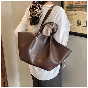 Detailed back view of a large brown wing-shaped tote bag worn as a shoulder bag