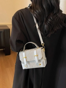 Silver pleated faux leather crossbody bag with gold clasps on black blazer outfit