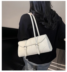 Detail view of white oil-wax leather baguette bag with silver buckles on shoulder