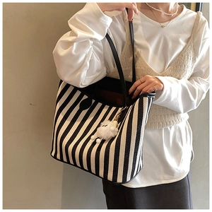 Close-up of black and white striped canvas tote bag with plush charm on a model