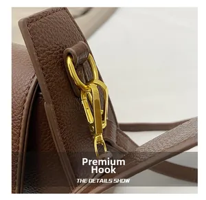 Detailed macro view of the premium golden metal hook on a brown textured leather bag