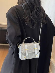 Retro silver wrinkled crossbody bag with gold hardware worn over a black blazer
