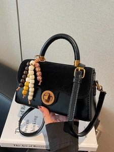 Retro black leather handbag with wooden bead pendant and metal twist lock on white books