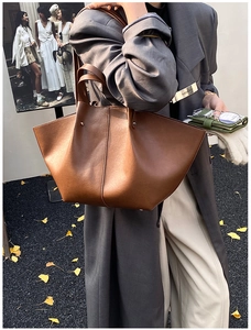 Close-up of caramel brown winged tote bag with glossy leather texture and stitched details