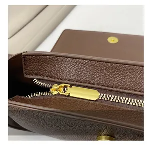 Macro detail of gold metal zipper and smooth lychee grain texture on brown leather bag