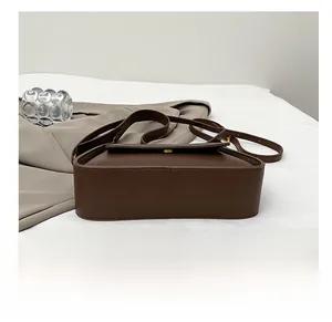 Detailed view of the brown lychee leather texture and durable bottom of the crossbody bag