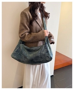 Close-up of vintage washed denim hobo bag with thick strap on a brown blazer outfit