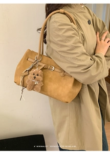 Λεπτομέρεια ρετρό τσάντας camel με γούρι αρκουδάκι πάνω από καμπαρντίνα