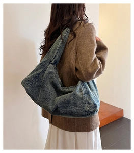 Detailed view of a retro denim hobo bag worn by a model to show its large capacity