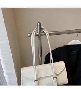 Detail of white oil-waxed leather baguette bag with silver hardware and adjustable straps