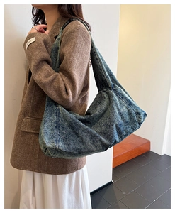 Detail of vintage blue washed denim hobo bag featuring thick fabric and wide shoulder strap