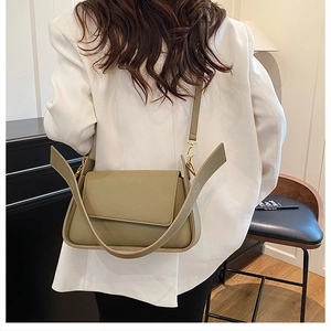 Detail view of sage green leather underarm bag with gold metal hardware and slim strap
