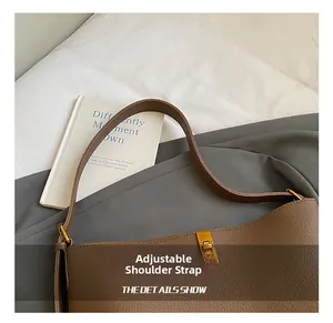 Détail de la bandoulière réglable en cuir et boucle dorée sur le sac seau marron