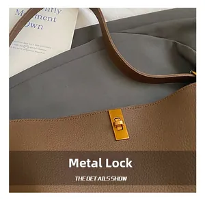 Gros plan sur le fermoir rectangulaire doré d'un sac seau en cuir de couleur marron foncé