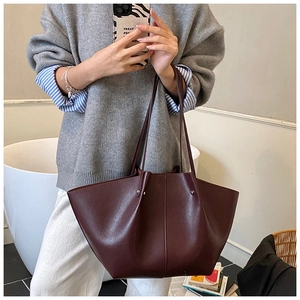 Deep wine red leather wing-shaped tote bag with stud details shown on model shoulder