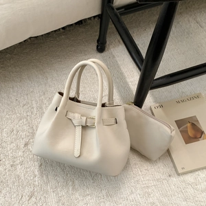 Detail view of cream leather tote with buckle strap and matching inner pouch set