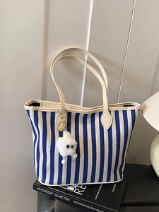 Blue and white striped canvas tote bag with a cute plush charm on a minimal background