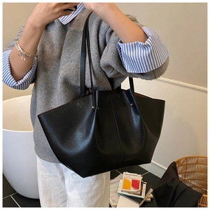 Detail of high-capacity black wing-shaped tote bag worn over the shoulder in daily life