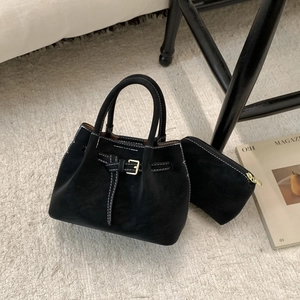Close-up of black suede tote bag with contrast stitching and matching small coin purse