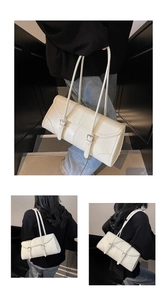 Detail view of cream rectangle underarm bag with double buckle straps in a lifestyle shot