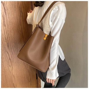 Détail du sac seau en cuir marron à motif litchi avec boucle dorée et logo en relief