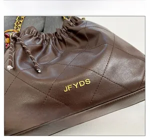 Macro detail of gold JFYDS metallic letters on brown quilted leather drawstring bag