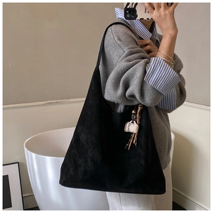Detail of vintage suede tote bag featuring a decorative coffee cup tassel pendant charm