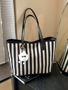 Large striped tote bag with leather handles and cute monster charm shown in a mirror
