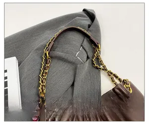 Detail of dark brown quilted tote bag with chain strap and elegant pleated leather finish