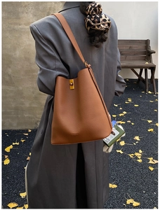 Détail d'un sac seau marron avec texture litchi, fermoir doré et style automnal chic