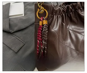 Detailed shot of dark brown quilted tote bag with a dual-color braided rope pendant