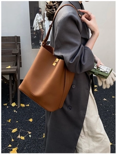 Détail d'un sac seau en cuir marron avec fermoir tournant doré et texture cuir grainé