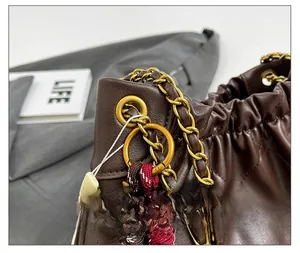 Detail of dark brown quilted leather bag featuring gold chain and braided rope accents