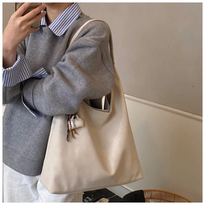 Close-up of minimalist cream tote bag with coffee cup charm showing large capacity